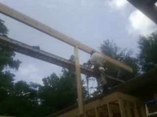 Carpenter setting a ridge beam over a new addition frame — Ice Dam Removal by Roofing Brothers in Mebane