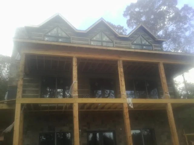 Dormers and porch framing on a large log home under construction — Roof Coating work by our crew in Mebane