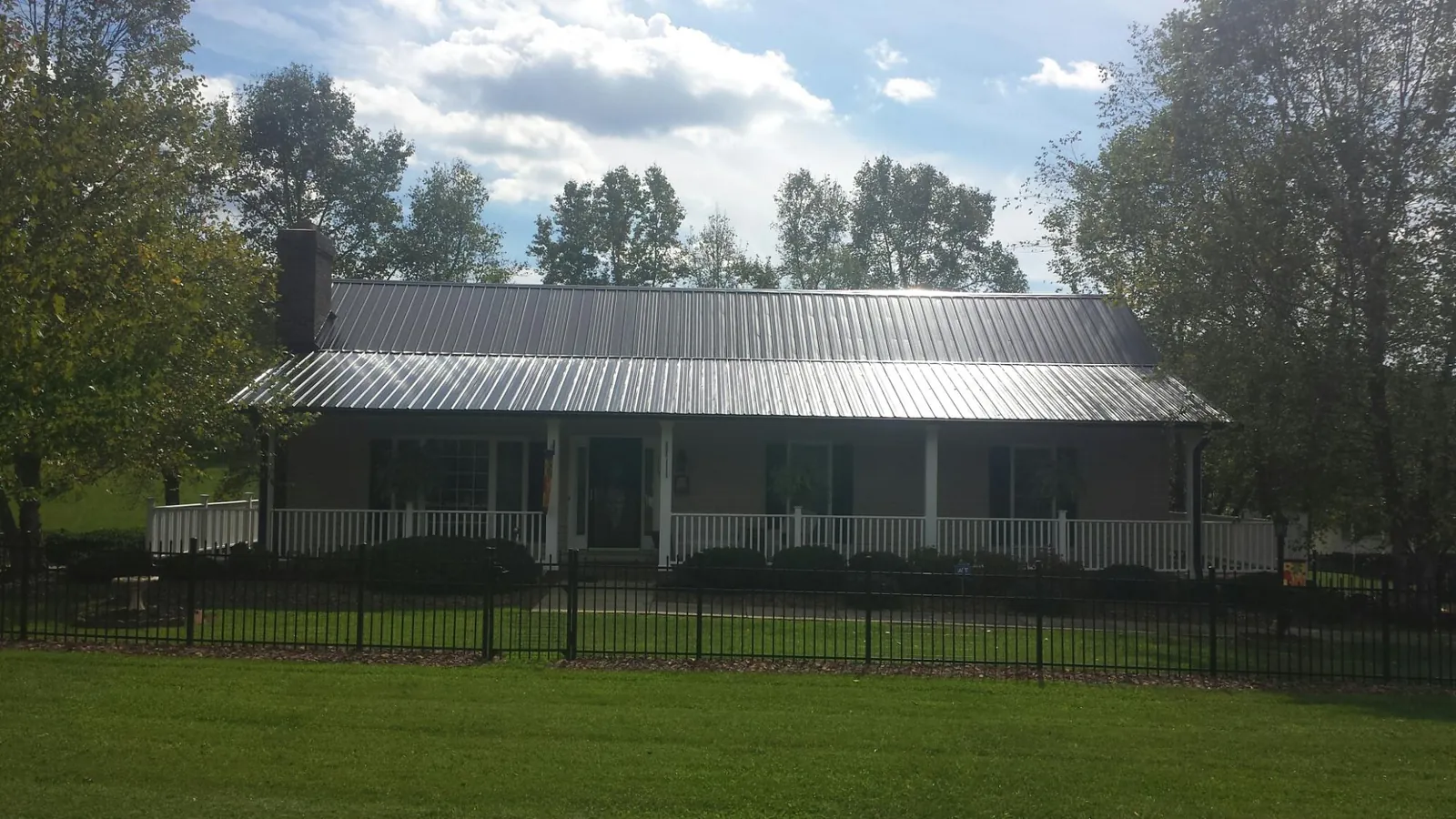 Gray metal roof on a brick ranch with a full width front porch — Gutter Guard Installation work by our crew in Mebane