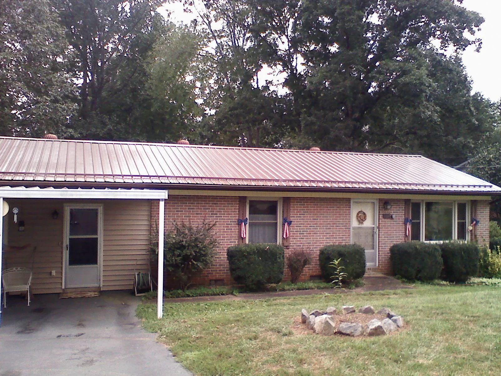 Bronze metal roof and carport on a brick ranch home — Roof Repair work by our crew in Mebane