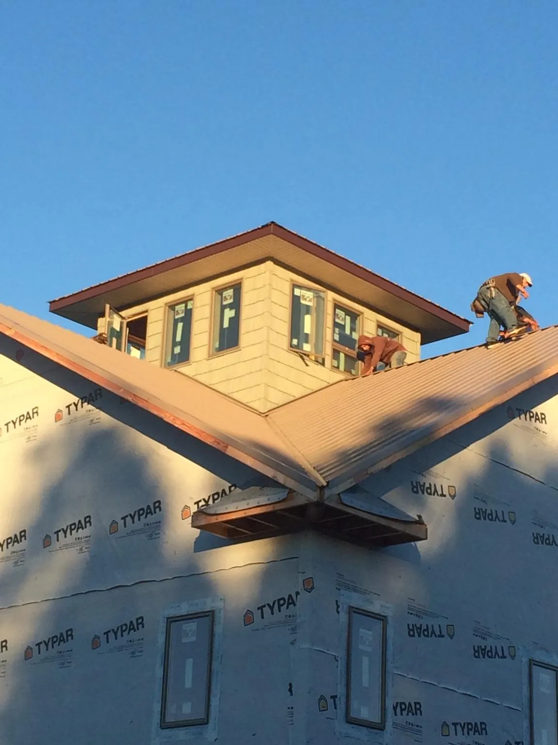 Roofers working around a rooftop cupola on a new metal roof at sunset — Roof Waterproofing in Mebane by Roofing Brothers
